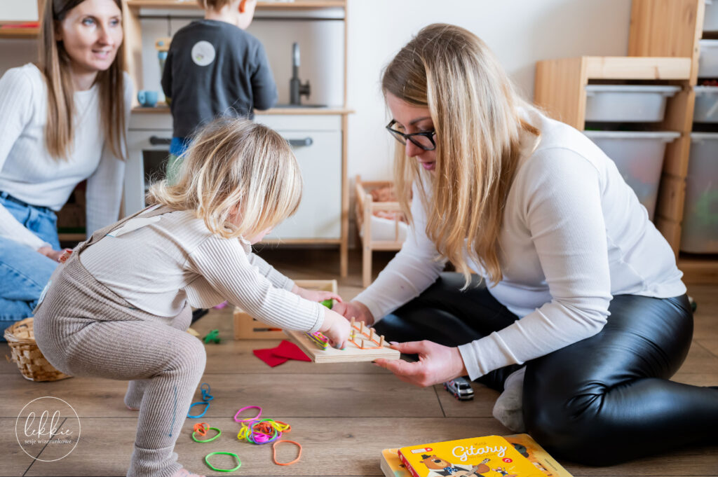 Mama i córka bawią się drewnianymi zabawkami w jasnej przestrzeni Żyrafiego Domku – adaptacja bliskościowa w praktyce.